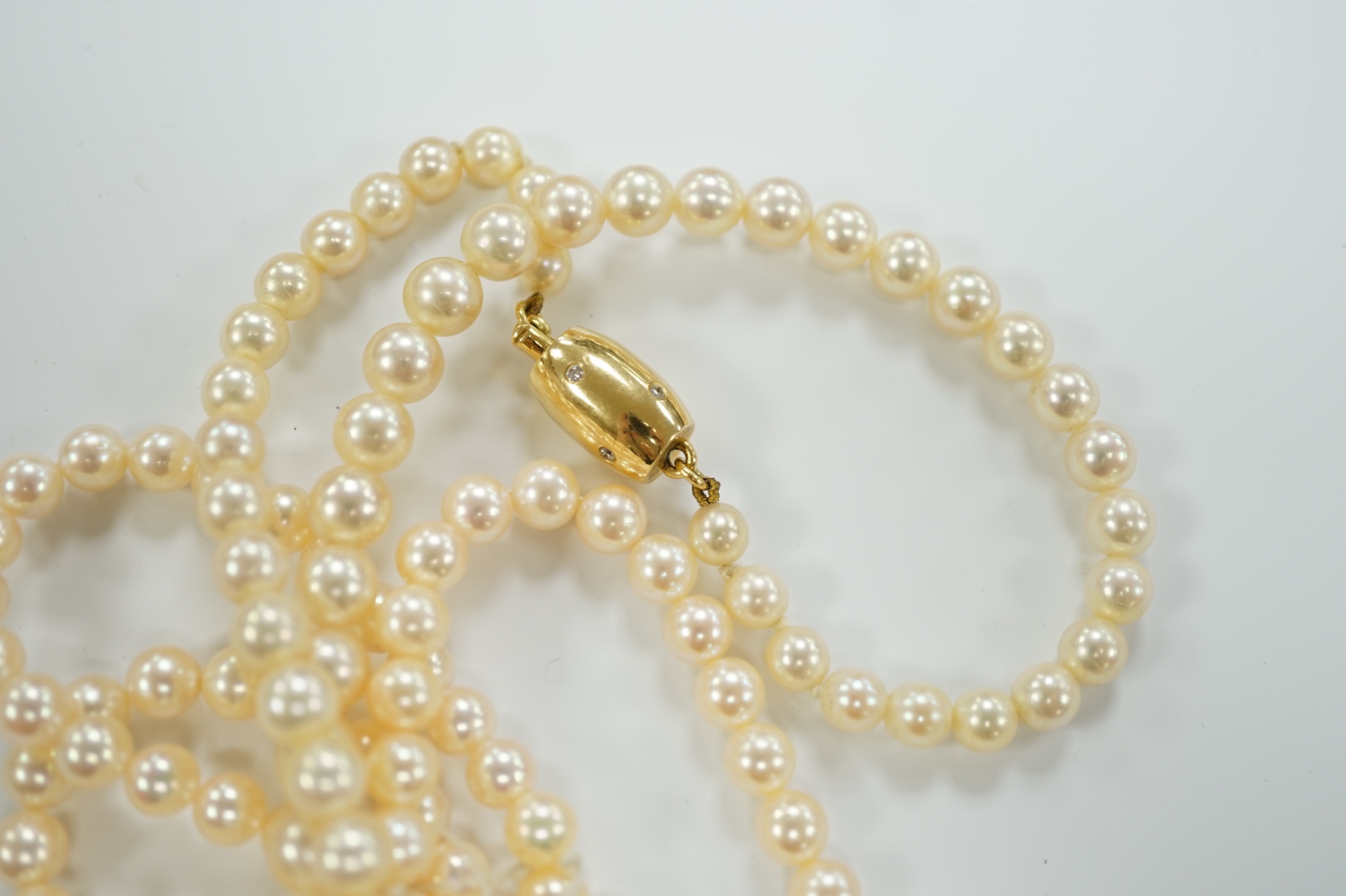 A single? strand cultured pearl necklace, with diamond inset barrel shaped yellow metal clasp (knotted).